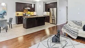 A modern kitchen with dark cabinets, stainless steel appliances, and a central island. - Pookah Bill House! (London)