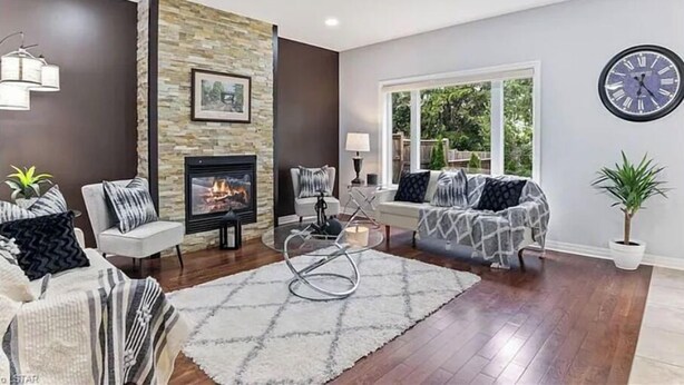 A modern living room with a fireplace, a sofa set, a coffee table, and a large window offering a view of greenery. - Pookah Bill House! (London)