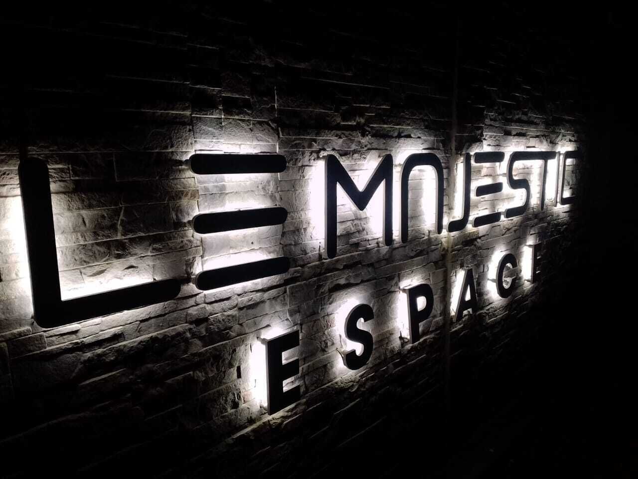 Un mur orné de lettres illuminées qui épellent les mots « LE MOJESTE ESPAG ».