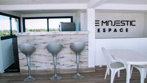 A modern kitchen with three bar stools, a white table, and a sign reading "EMNESTIC ESPACE". - Espace le Majestic Toamasina (Toamasina)