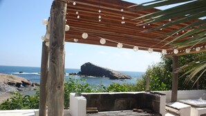 A wooden pergola with string lights, overlooking a beach with a rocky outcrop and the sea. - Apartment right on the beachfront! - Beach - SweetHomeRooms (Cabo de Palos)
