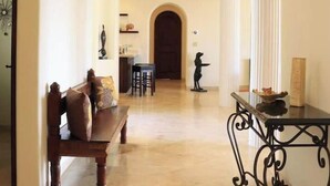 A spacious hallway with a stone ceiling, a wooden bench, a black metal table, and a door leading to a room. - Villa de Lujo Buena Vista 3 (Cabo San Lucas)