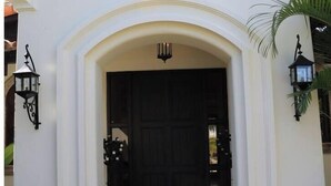 A white entrance with a black door, flanked by two black lantern-style lights. - Villa de Lujo Buena Vista 3 (Cabo San Lucas)