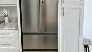A stainless steel Haier refrigerator in a kitchen with white cabinetry and marble countertops. - Sea Glass at the Reef - Luxury King Beach Front Condo On The Beach (Colliers Bay)