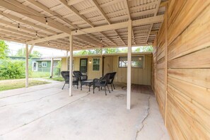 A covered patio area with a concrete floor, wooden walls, and a table with chairs. - Walk to TX State -  Kitchenette - Workspace - Pet Friendly - Monthly Available (San Marcos)