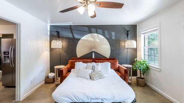 Une chambre à coucher avec un lit, un ventilateur de plafond, des appliques murales et une fenêtre.