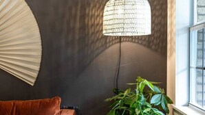 Un coin douillet avec un canapé en cuir marron, une petite table ronde, une plante en pot et une grande lampe en fibres tressées.