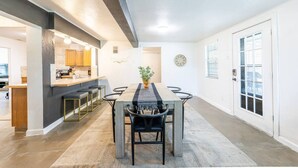 Un espace de restauration moderne avec une longue table, des chaises noires et une plante placée au centre.