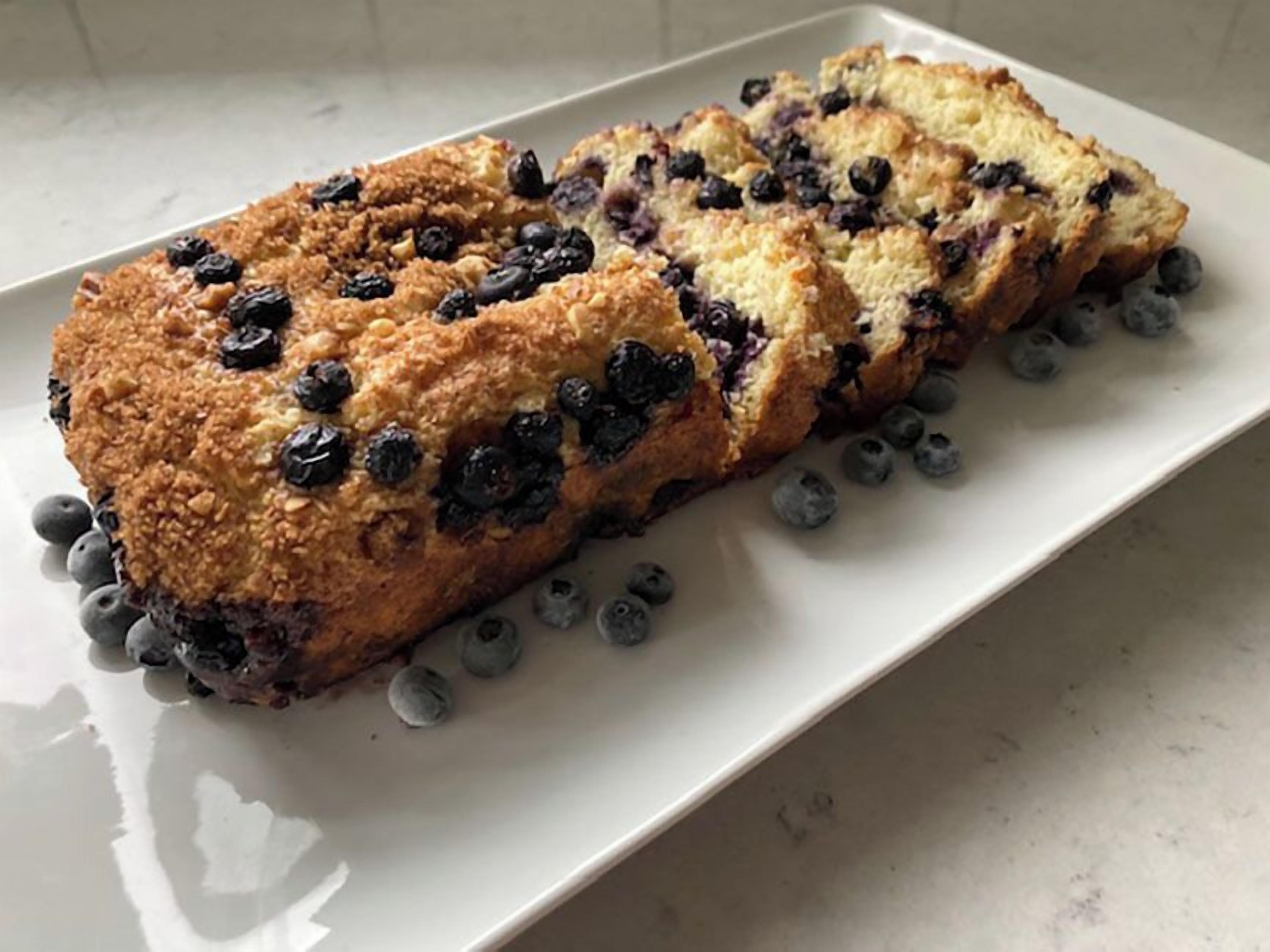 Een sneed blauwe bessenbrood op een wit bord.