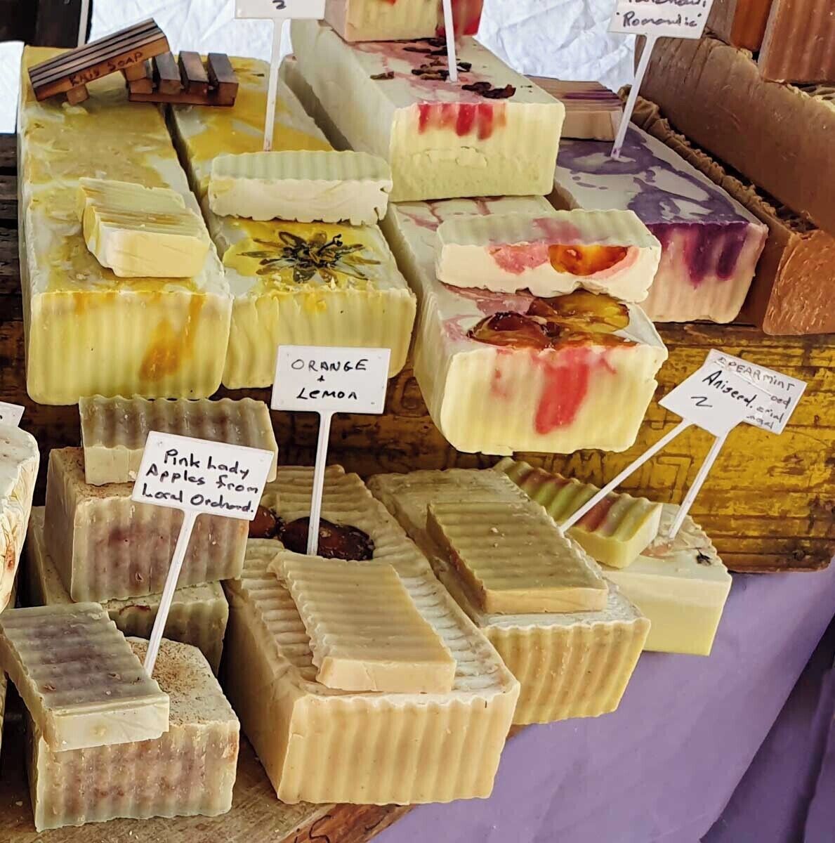 Variedad de jabones de distintos aromas y colores sobre una superficie de madera.