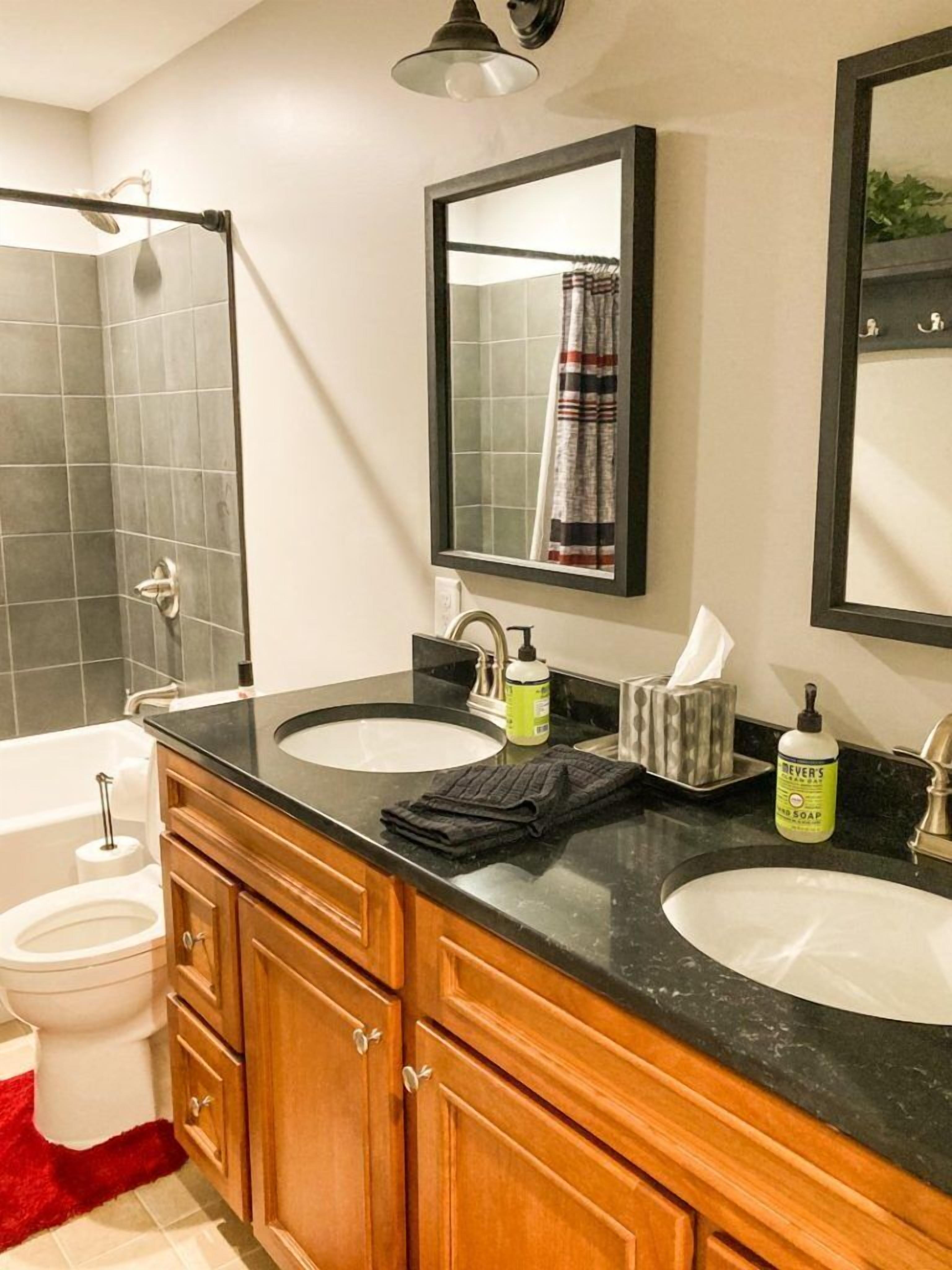 A bathroom with two sinks, a toilet, and a shower.