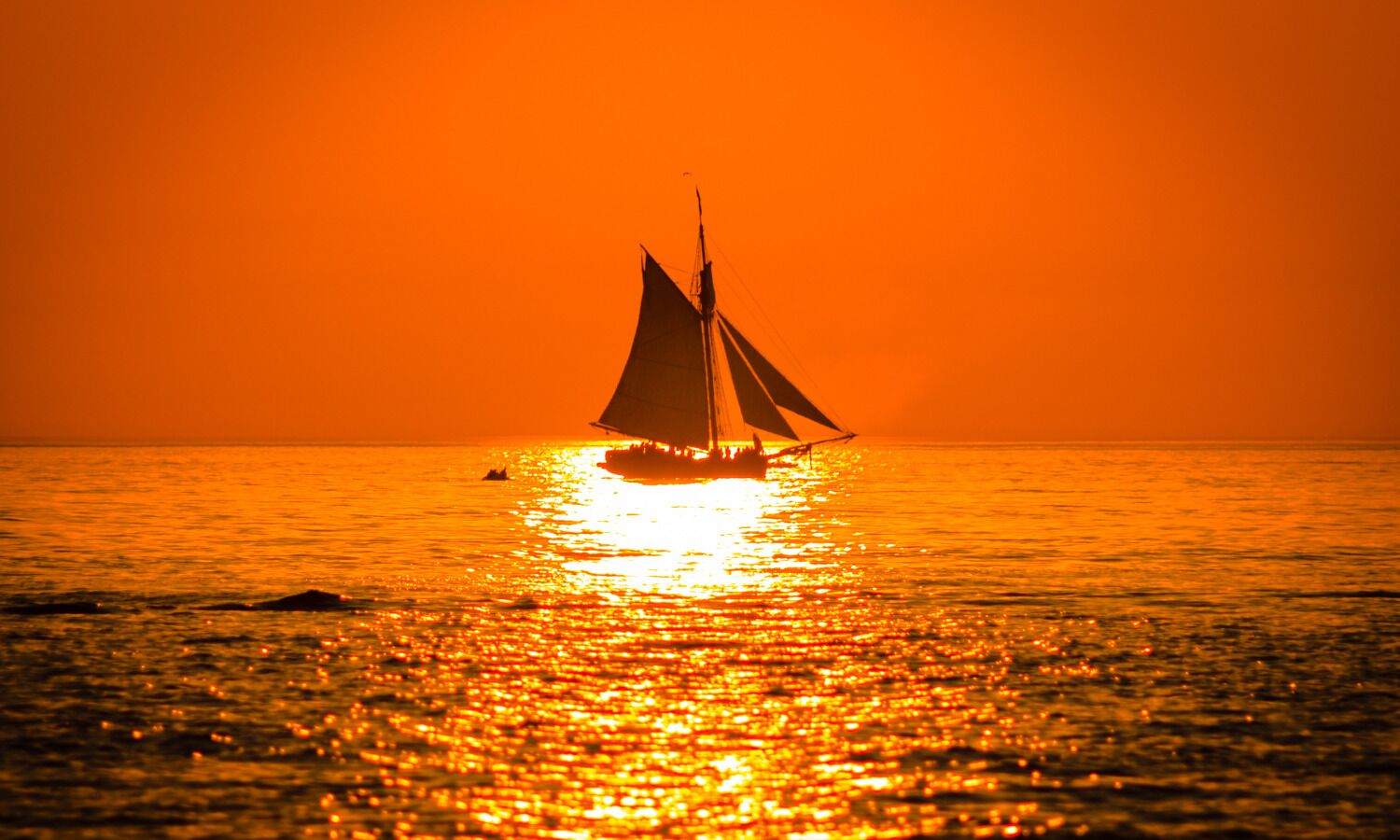 Ein Segelboot auf ruhigem Wasser bei Sonnenuntergang.