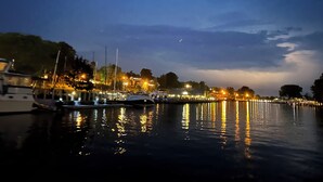 Un port de plaisance au crépuscule, avec des bateaux amarrés et leurs reflets sur l’eau.