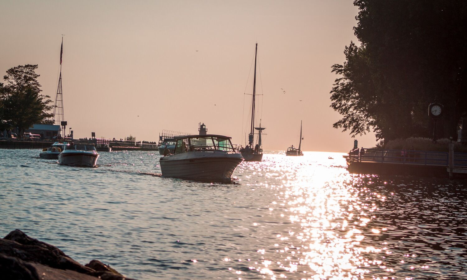 Un puerto deportivo con barcos amarrados, agua tranquila y un atardecer de fondo.