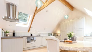 Une cuisine moderne avec des meubles blancs, un plafond en bois et un coin repas comprenant une table et des chaises.