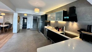 A modern kitchen with a central island, built-in appliances, and a dining area with a table and chairs. - Panoramic Villa with jacuzzi (Bodrum)