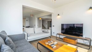 A modern living room with a grey sofa, a wooden coffee table, and a flat-screen TV. - Panoramic Villa with jacuzzi (Bodrum)