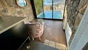 A balcony with a view of a pool and mountains, a round mirror on the wall, and a floral armchair. - Panoramic Villa with jacuzzi (Bodrum)
