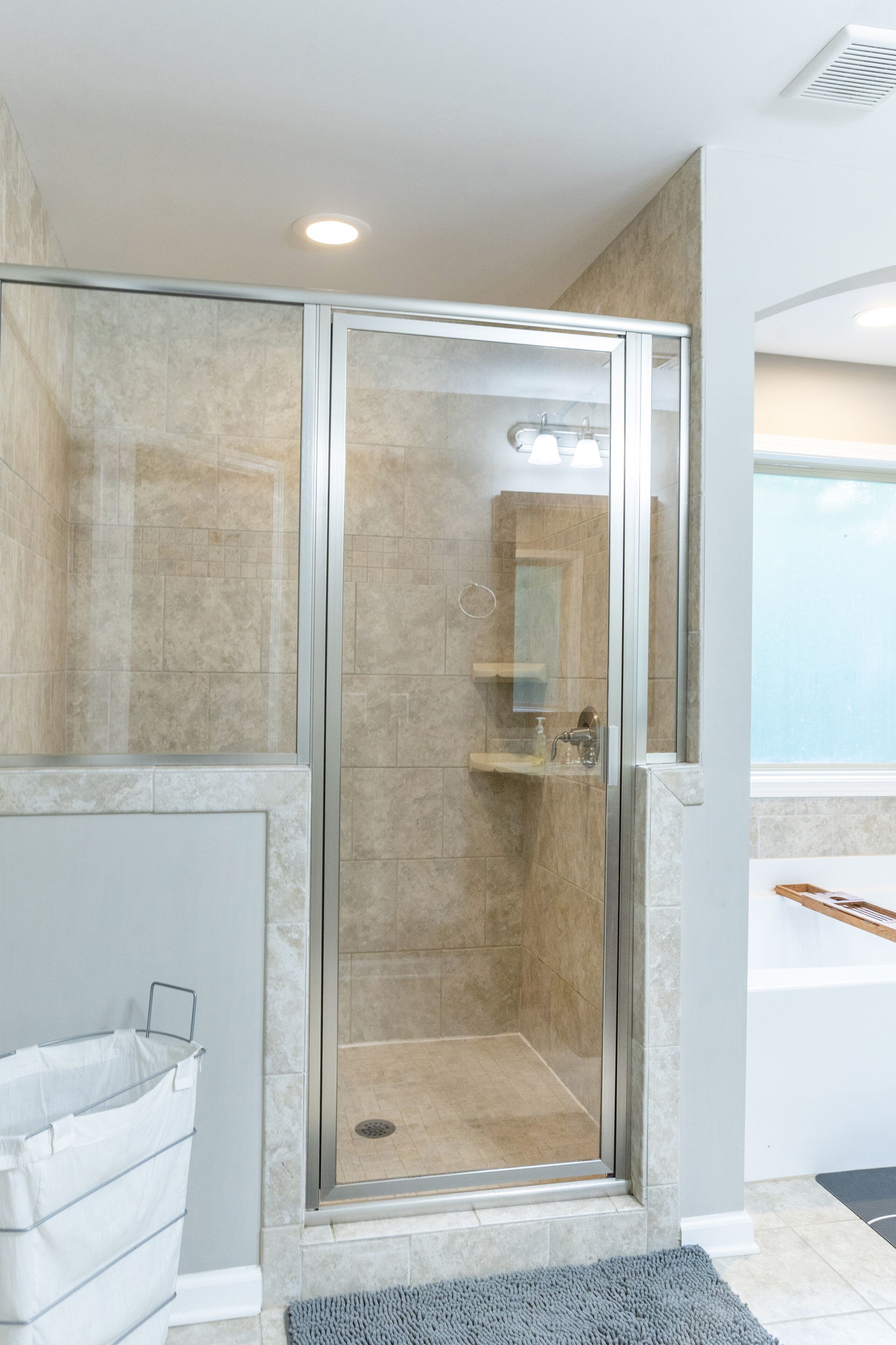 A glass-enclosed shower area with a tiled floor and a small shelf.