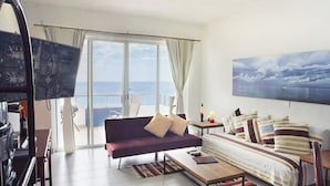 Ein Zimmer mit großem Fenster, einer Couch, einem Bett und einem Tisch.