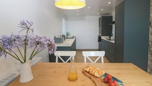 Eine moderne Küche mit einem Holztisch, einer Blumenvase und einer Orangensaftflasche.
