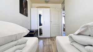 En smal gang med senge på hver side, der fører hen til en dør med et spejl og et lille bord.