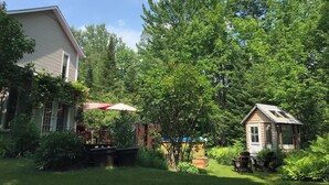 A backyard with a house, a small shed, and a red umbrella. - Intimité et Confort, Plusieurs Foyers, à Proximité D'activités et Sherbrooke (Sherbrooke)