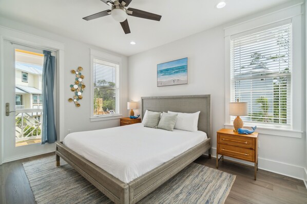 A bedroom with a large bed, two bedside tables, a ceiling fan, and a window with blinds.