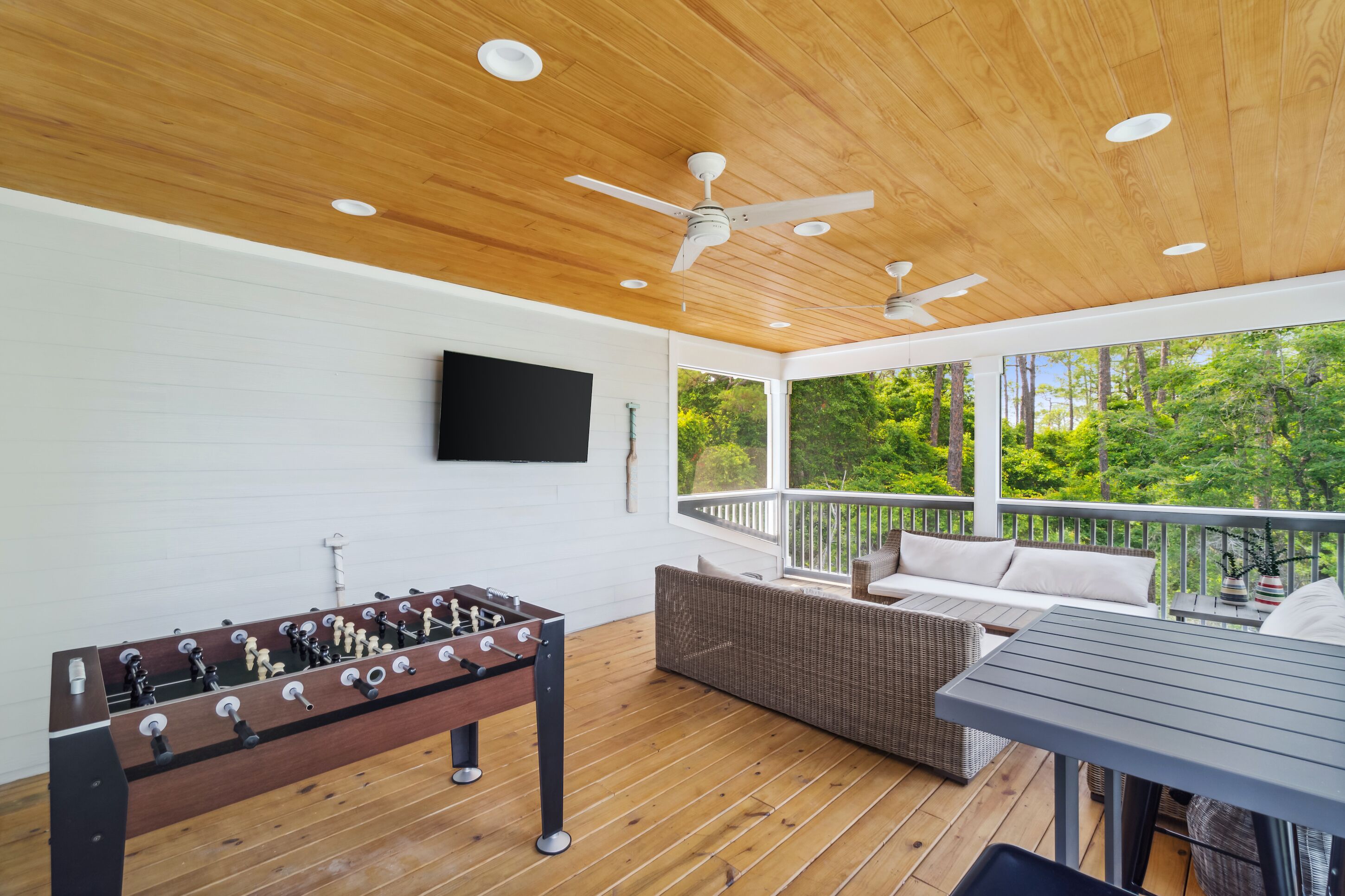 A wooden deck with a foosball table, a sofa, and a table with chairs.