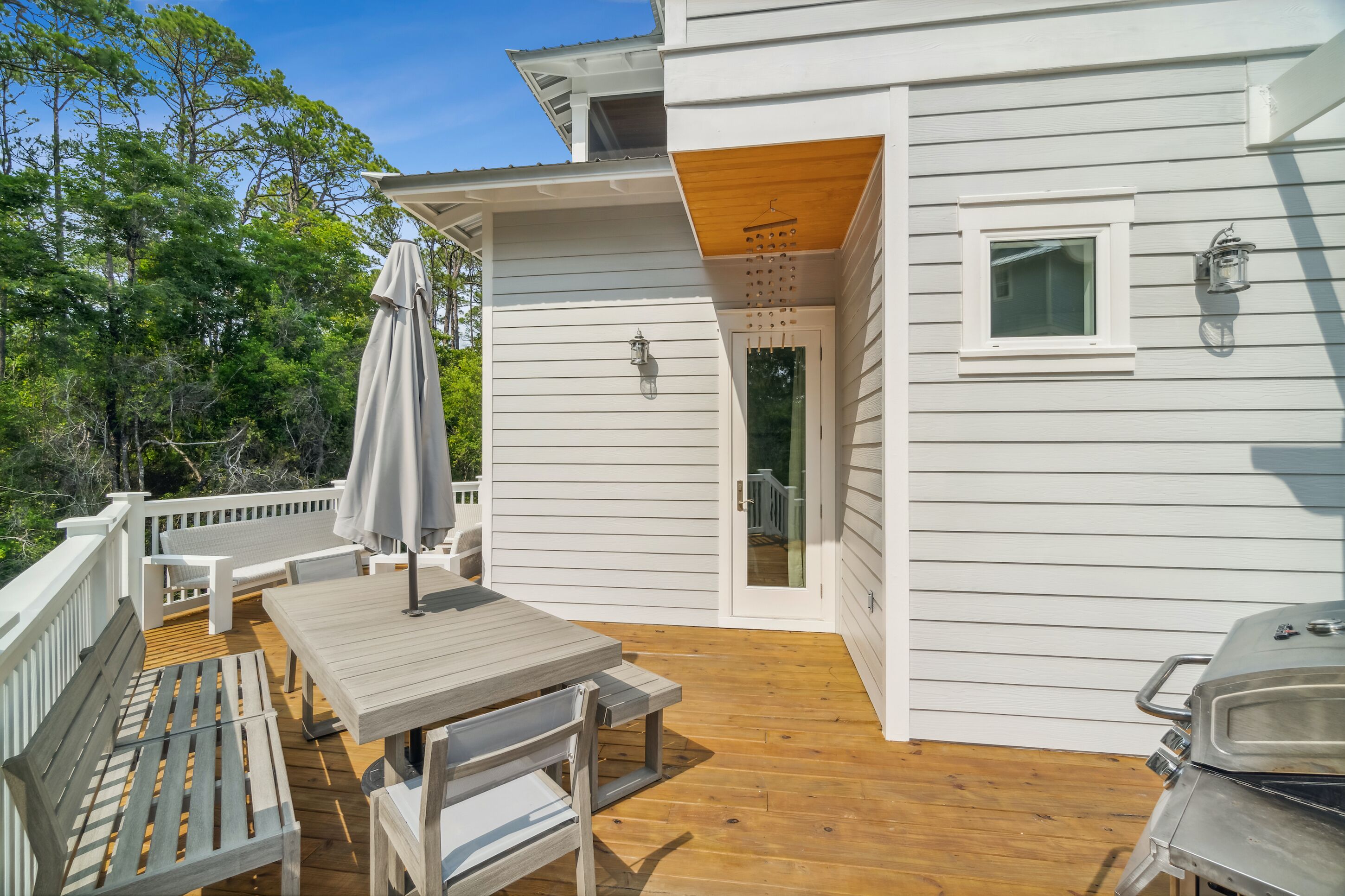 A deck with a table and chairs, a grill, and a covered seating area.