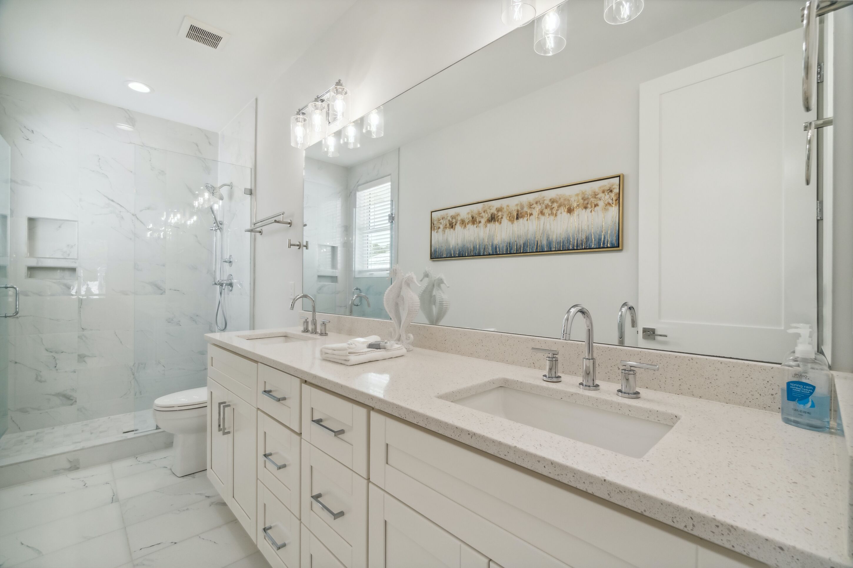 A modern bathroom with a double sink, a large mirror, and a shower.