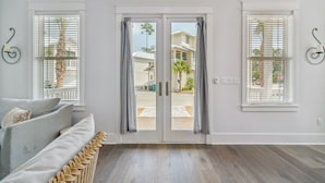 A room with a light-colored sofa, a wicker chair, and a sliding glass door leading to a patio. - 30A Beach House - 30A Wonderland by PHG (Panama City Beach)