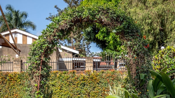 A stone staircase leading up to a house with a brick wall and a metal fence. - Fred and Winnie BnB (Kampala)