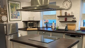 A modern kitchen with a central island, stainless steel appliances, and a decorative bird sculpture. - Cozy vacation apartment with complete equipment for up to 5 people (Bötersen)