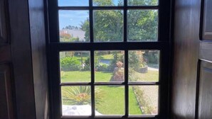 A window with a view of a well-maintained garden and a distant building. - Relax in Casa Pousadela with Garden 5 km from the sea (Nogueira Da Regedoura)