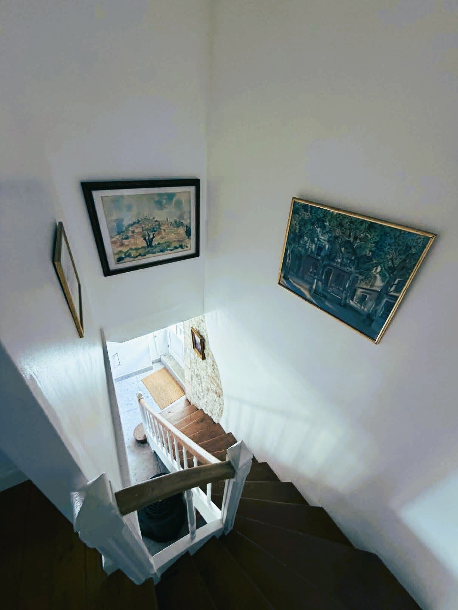 Una scala con pareti bianche e due opere d'arte incorniciate.