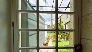 A door with a grid of glass panes, leading to an outdoor area with a lawn and potted plants. - Charming Cottage with exclusive use of the Jacuzzi upon request
 (Val-de-Bonnieure)