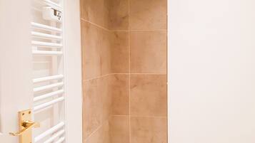 A bathroom with beige tiles, a white radiator, and a wooden floor.