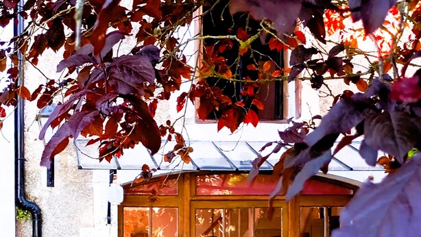 A courtyard with a wooden door, a small table, and chairs. There are potted plants and a gravel path. - Charming Cottage with exclusive use of the Jacuzzi upon request
 (Val-de-Bonnieure)