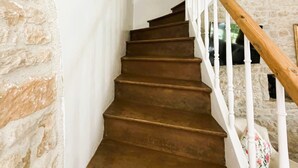 A staircase with wooden steps and white railings, leading to a room with stone walls and a framed picture on the wall. - Charming Cottage with exclusive use of the Jacuzzi upon request
 (Val-de-Bonnieure)
