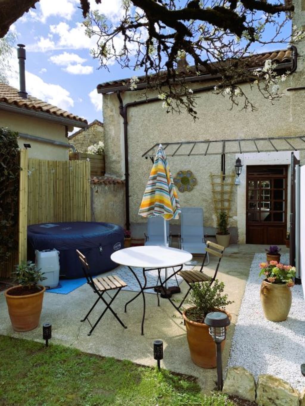 Un patio con jacuzzi, mobiliario exterior y plantas en macetas.