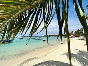 Ein Strand mit klarem türkisblauem Wasser, Booten und Palmen.