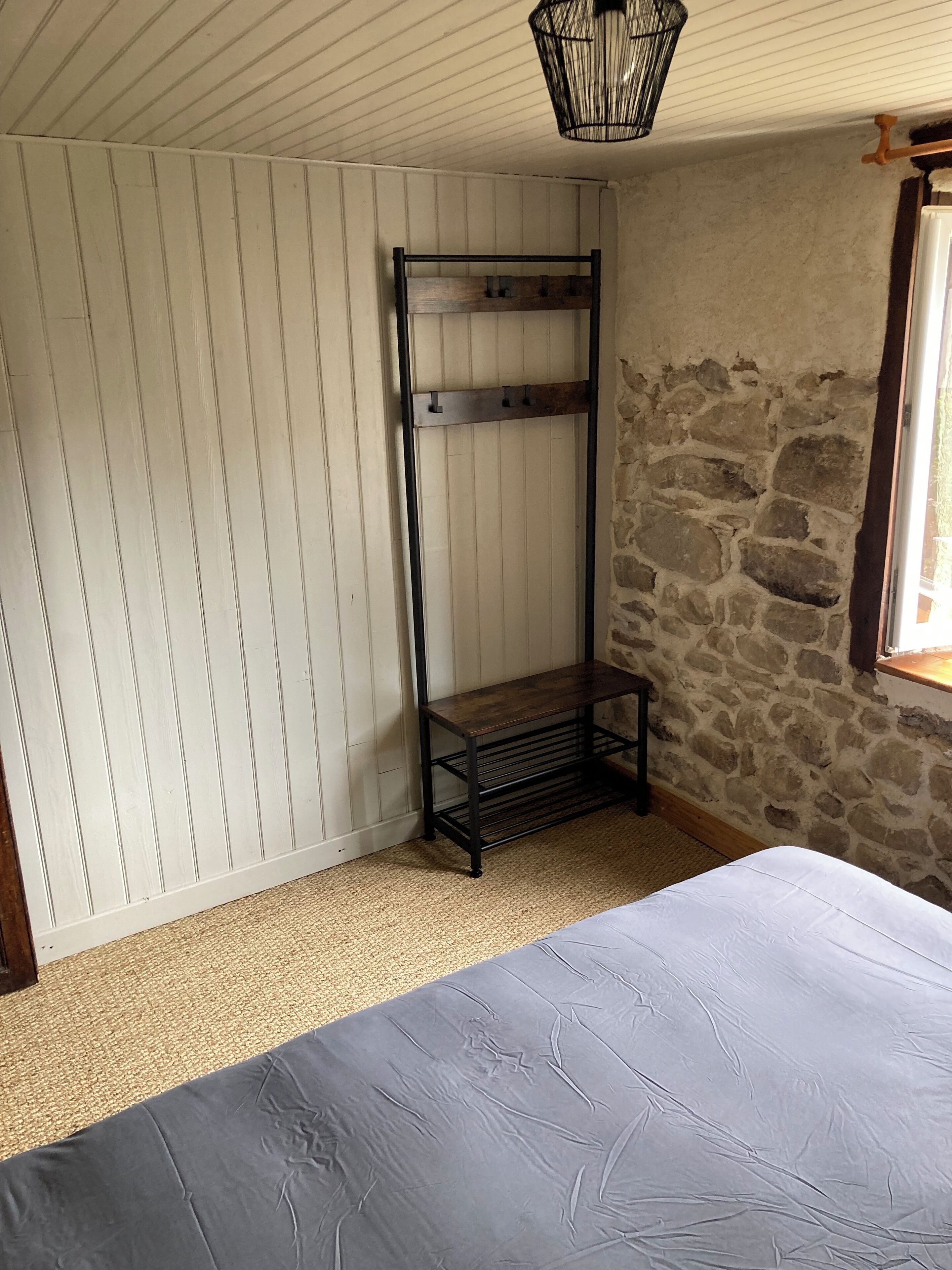 A room with a bunk bed, a stone wall, and a window.