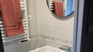 Ein Badezimmer mit einem weißen Waschbecken, einem Spiegel und einem Handtuchhalter mit einem roten Handtuch.