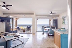 Enjoy a panoramic ocean view from this spacious living area with a dining table, kitchen, and seating area.