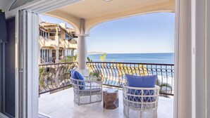 Un balcone con sedie in vimini e vista sul mare.