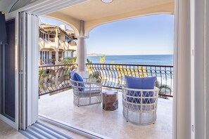 Enjoy the ocean view from this balcony with two comfortable chairs and a stool.