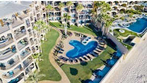 Un resort con diversi balconi, una piscina centrale e vegetazione circostante.