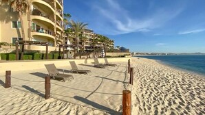 Un hotel sulla spiaggia con diversi balconi, sdraio e vista sull'oceano.