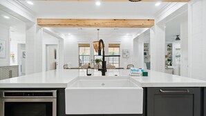 A modern kitchen with white cabinetry, a stainless steel dishwasher, and a built-in oven. - 30A Beach House - Dream Chaser by PHG (Santa Rosa Beach)